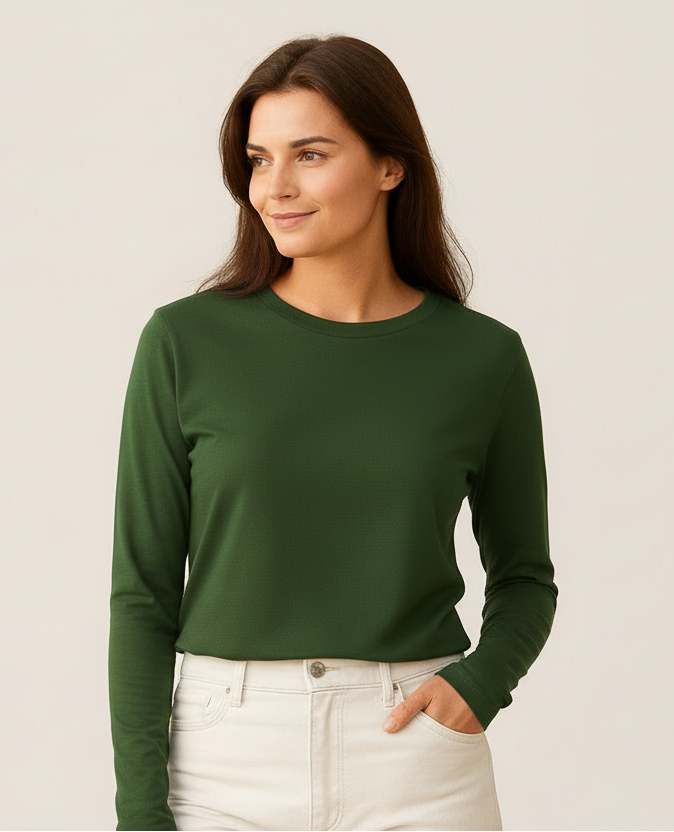 Woman wearing a green sweater and white pants against a plain background