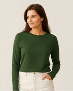 Woman wearing a green sweater and white pants against a plain background
