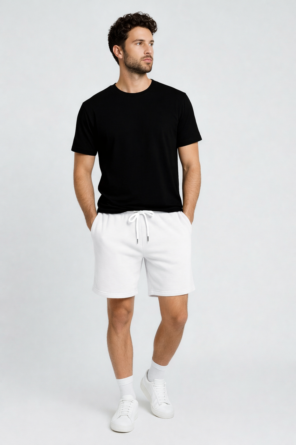 Man wearing a black t-shirt and white shorts on a plain background
