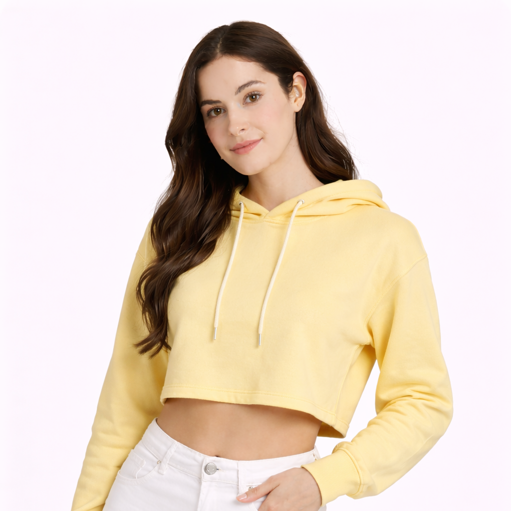 Woman wearing a yellow cropped hoodie and white pants on a white background
