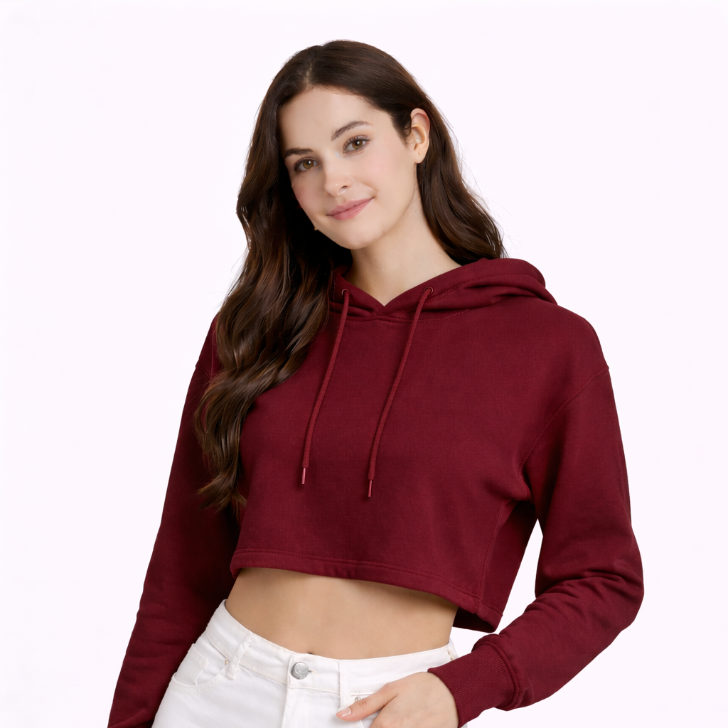 Woman wearing a burgundy cropped hoodie and white pants on a white background