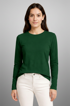 Woman wearing a green long-sleeve shirt and white pants on a beige background