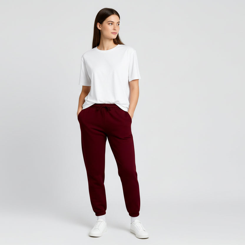 Woman wearing a white t-shirt and maroon pants on a light gray background